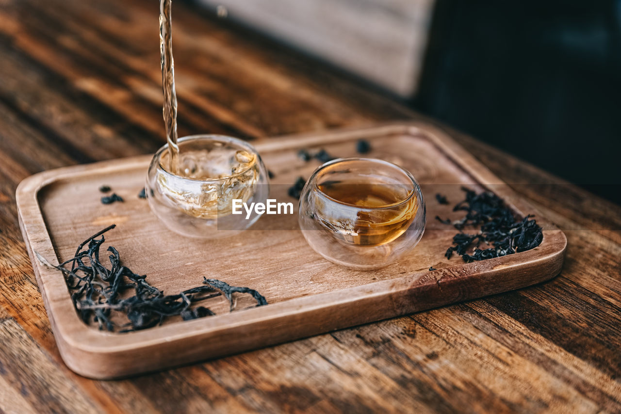 High angle view of drink pouring in drinking glass on wooden tray