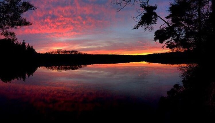 SCENIC VIEW OF CALM LAKE AT SUNSET