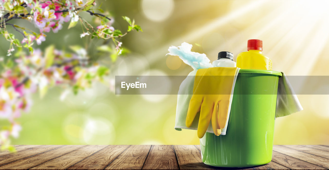 CLOSE-UP OF YELLOW BOTTLE ON TABLE AGAINST BLURRED BACKGROUND