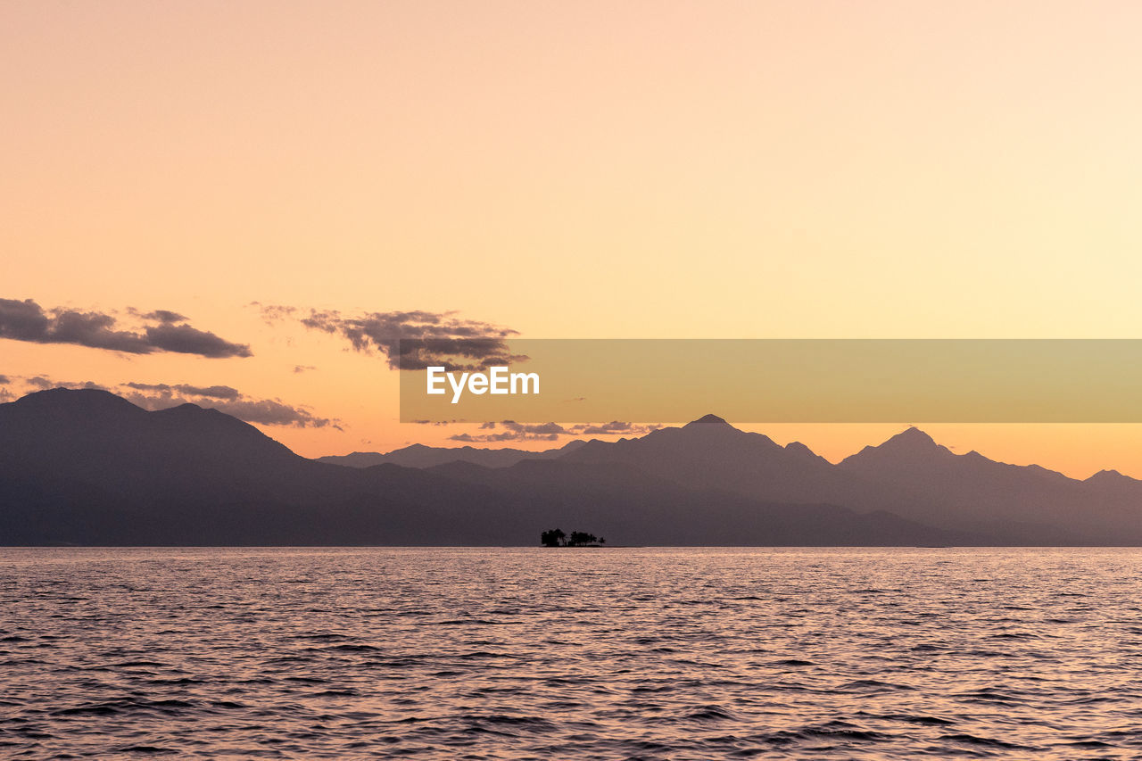SCENIC VIEW OF SEA AND MOUNTAINS AGAINST SKY DURING SUNSET