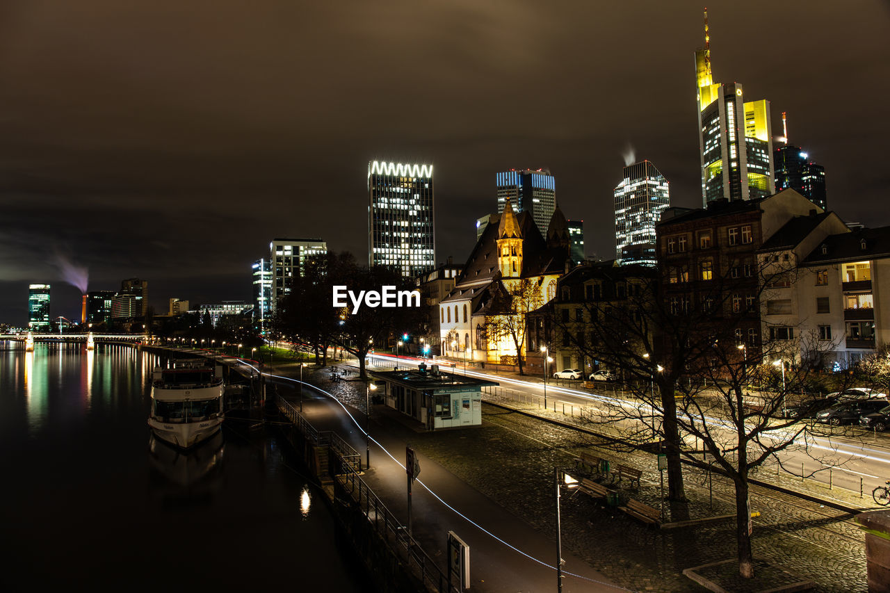 ILLUMINATED CITY BY BUILDINGS AGAINST SKY AT NIGHT