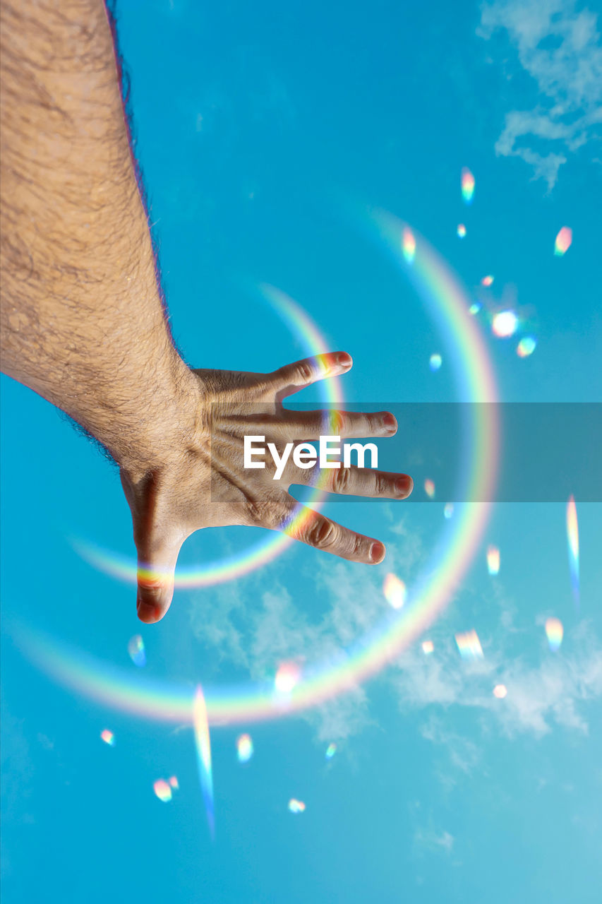 low angle view of hand against blue sky