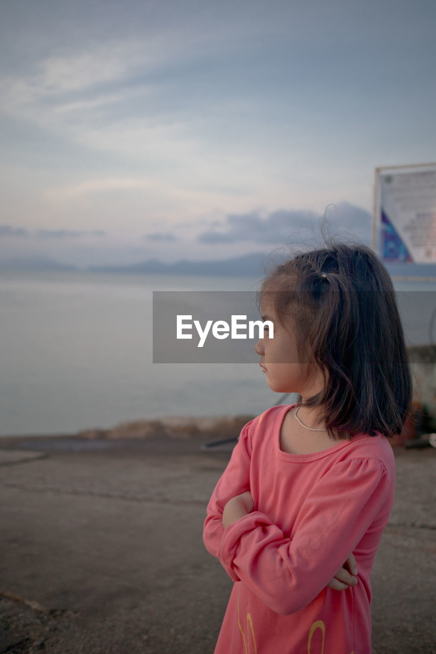 Girl looking at camera against sky during sunset