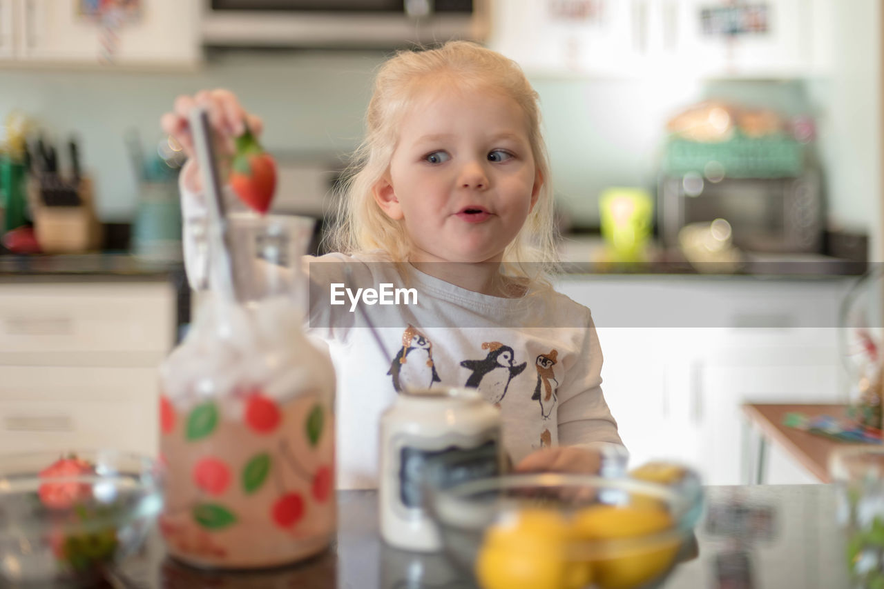 Cute girl having strawberry at home