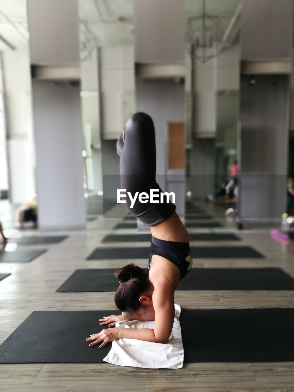 Side view of woman practicing handstand at gym