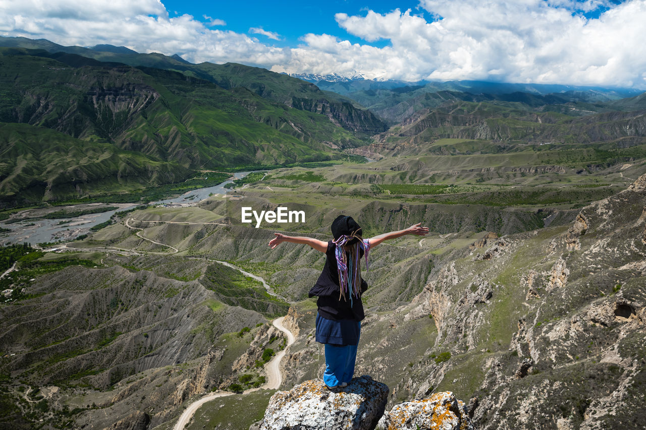 Rear view of man looking at mountains against sky