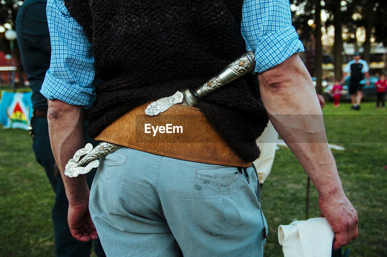 Midsection of man with dagger standing in park