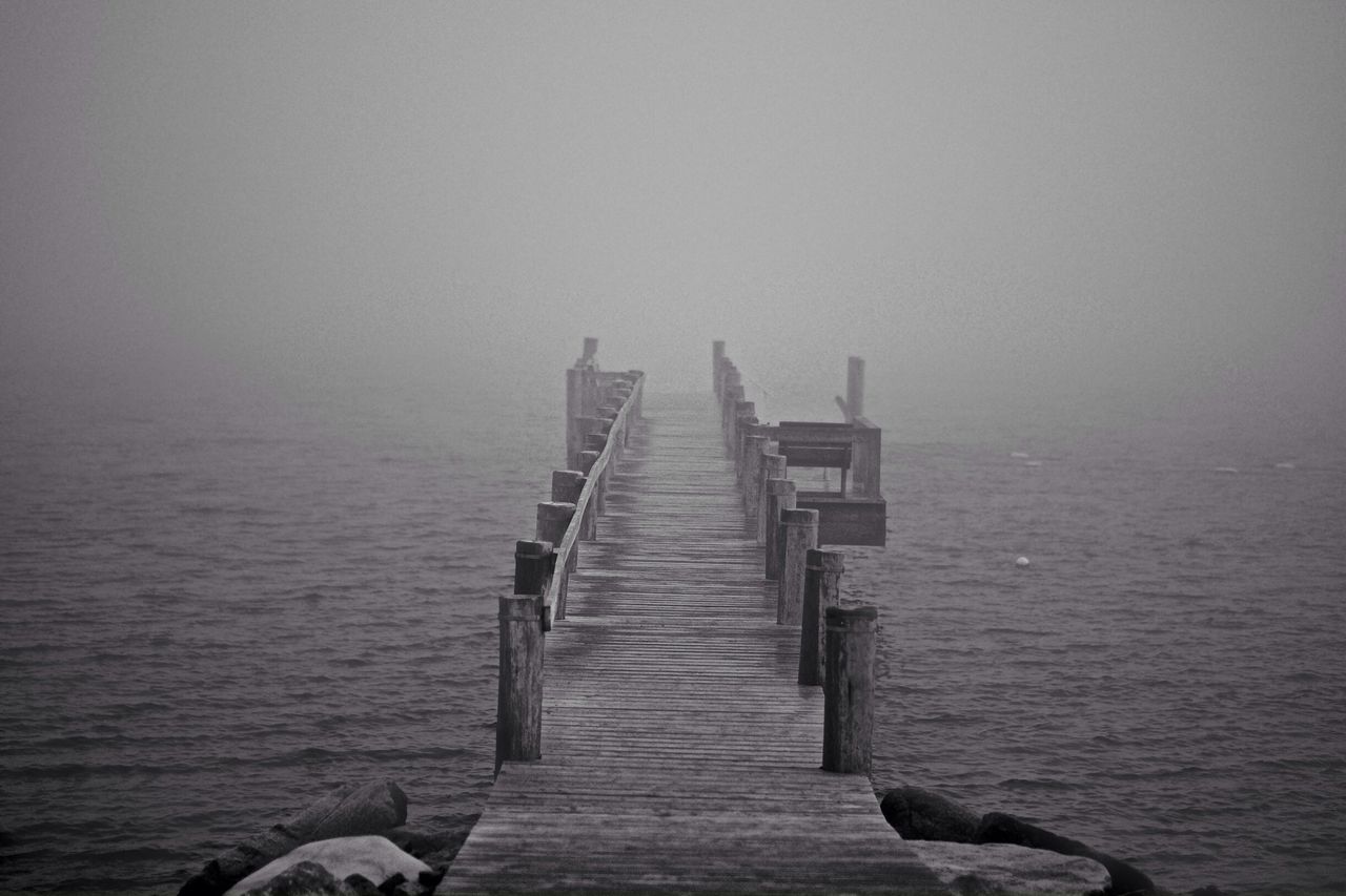 Wooden pier over river during foggy weather