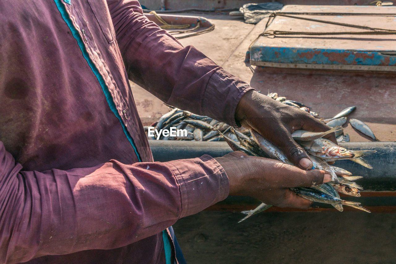 Midsection of man holding fishes outdoors