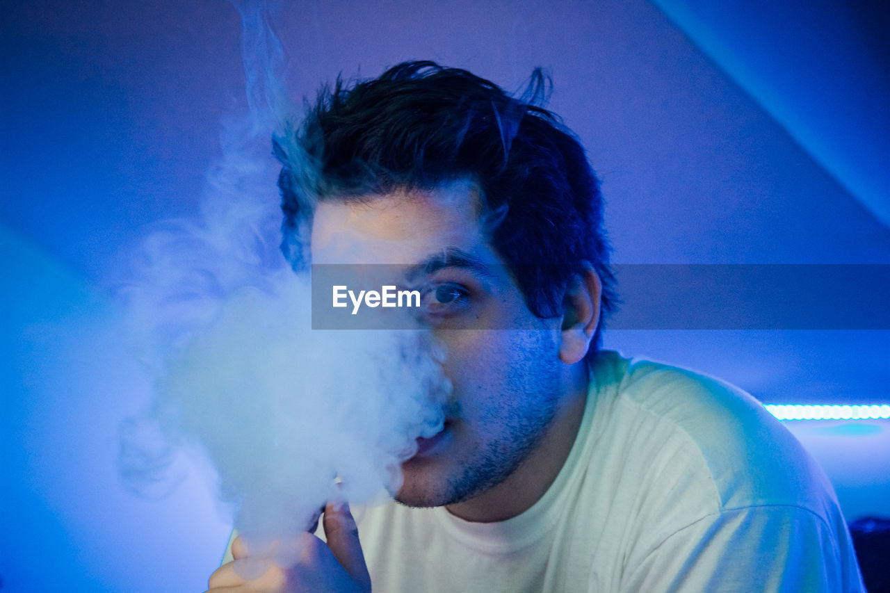 Close-up portrait of young man smoking in club