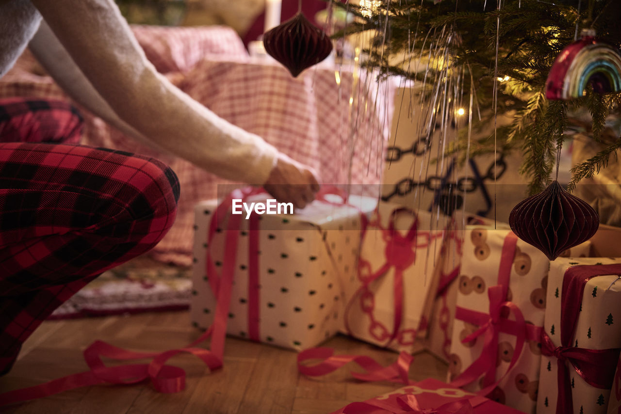 Person wrapping present under christmas tree