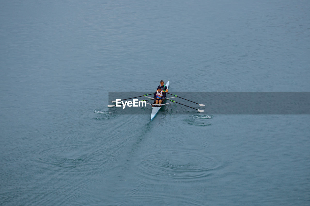 water, nautical vessel, transportation, rowing, sports, oar, men, mode of transportation, nature, high angle view, boating, teamwork, day, cooperation, water sports, adult, sculling, recreation, competition, lake, motion, togetherness, rowboat, outdoors, copy space, lifestyles, sport rowing, athlete, boat, vehicle, waterfront, two people, paddle, scull, clothing, sports clothing, leisure activity, player, blue, vitality, young adult