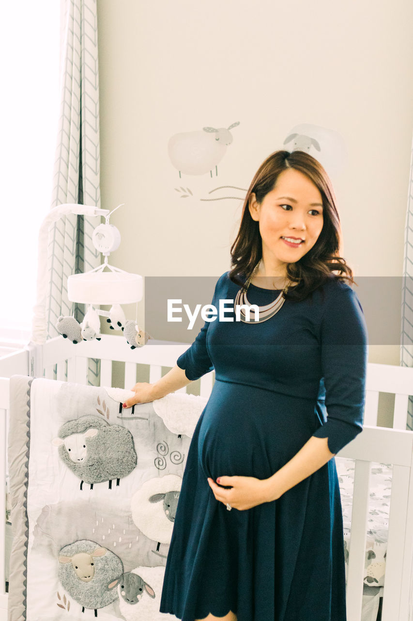 PORTRAIT OF HAPPY WOMAN STANDING AGAINST WALL