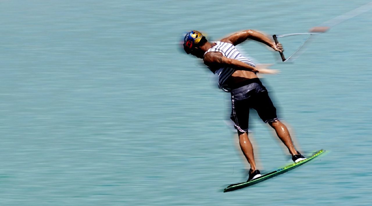 Blurred motion of wet man wakeboarding in sea