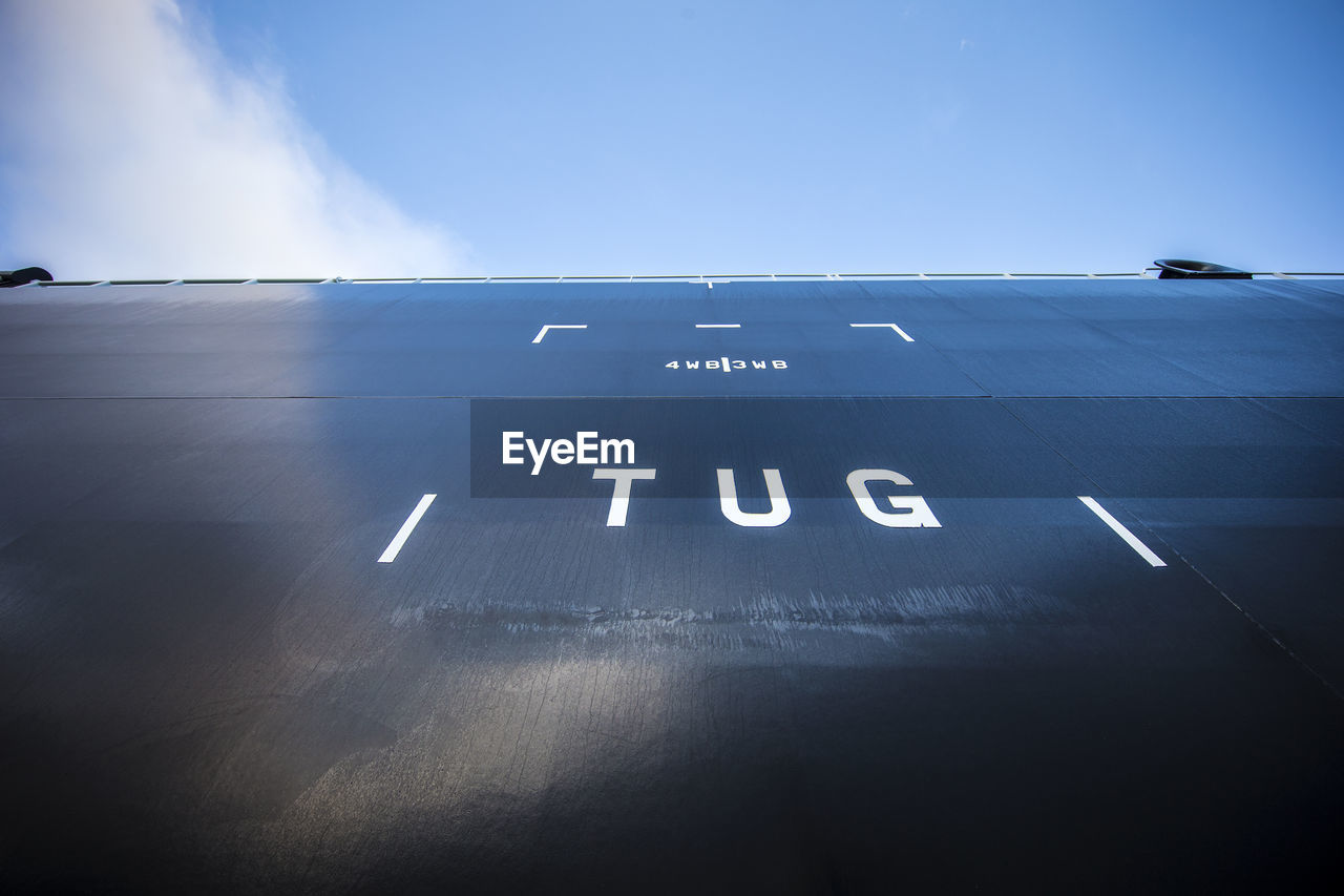 Low angle view of tug text on ship against sky