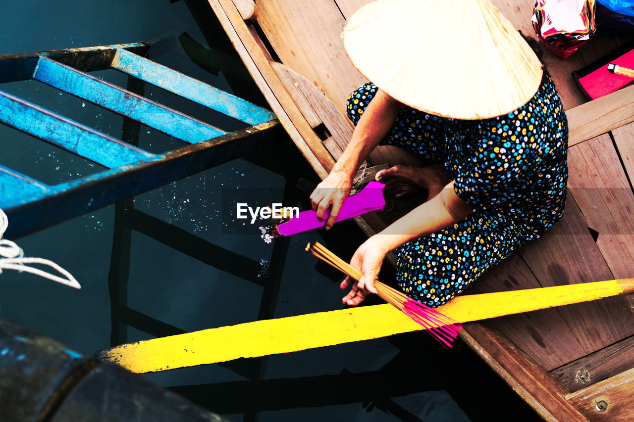 High angle view of woman burning incense sticks in boat