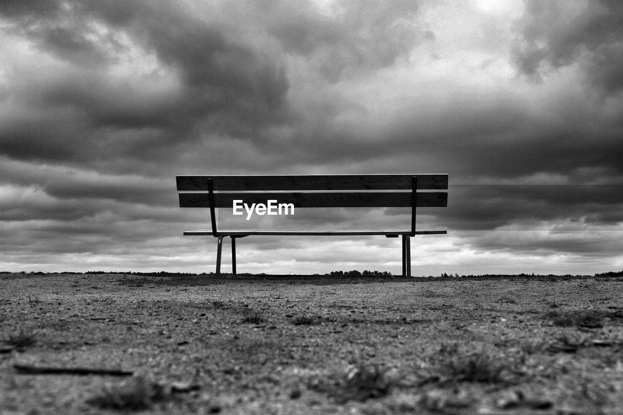 Abandoned bench with dark clouds