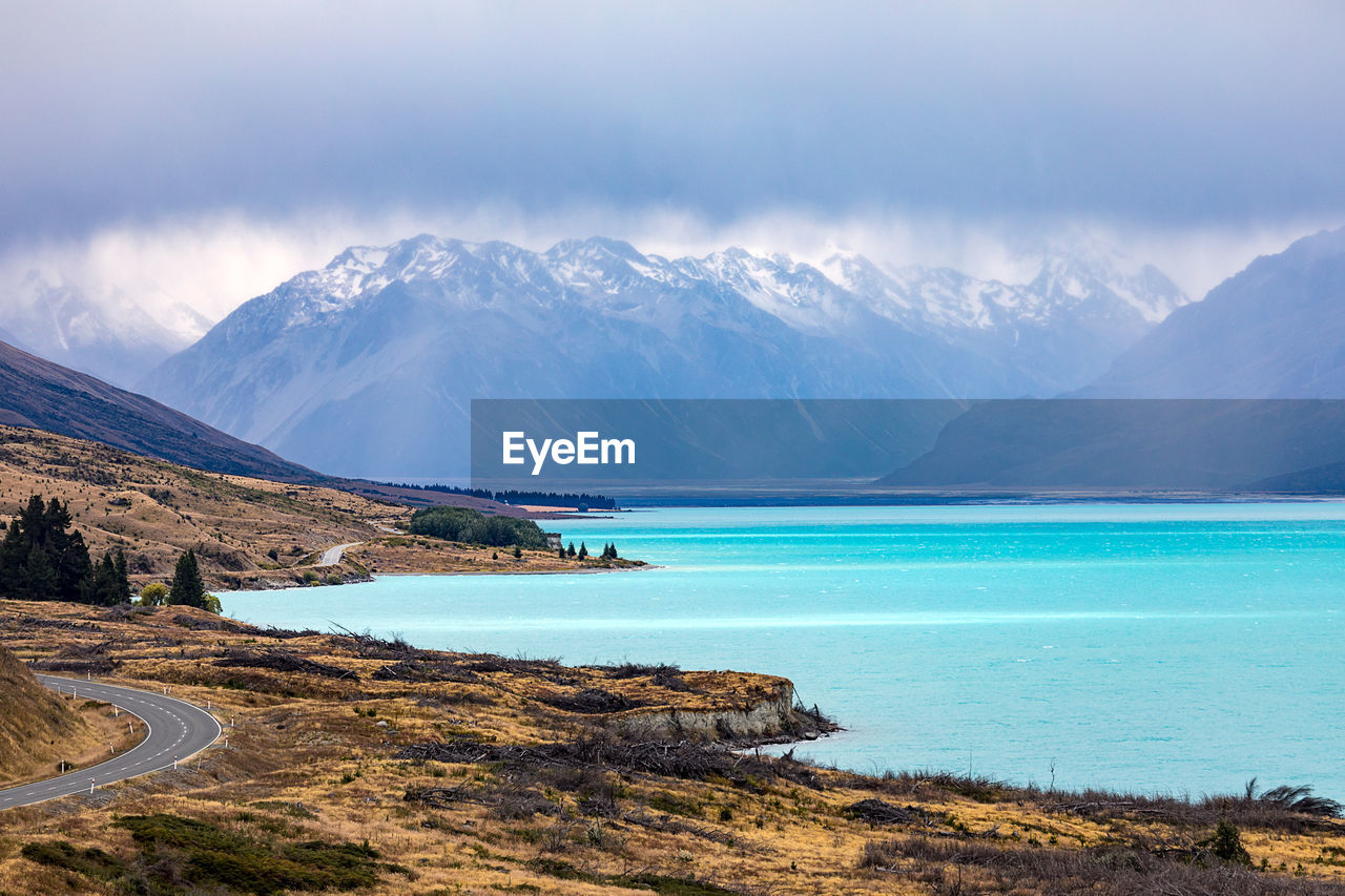 Scenic view of lake and mountains against cloudy sky