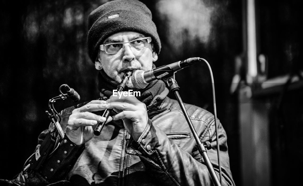 Portrait of man playing flute on stage in black and white 