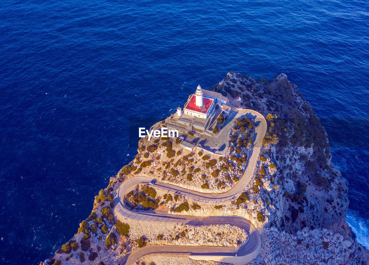 Aerial view of lighthouse on cliff by sea