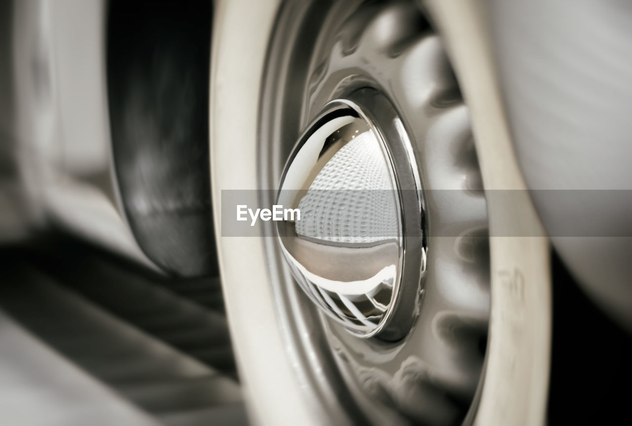 Close-up of car tire with building reflection