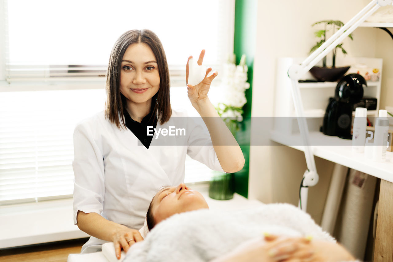 Portrait of a beautician girl with a gouache scraper in her hand while working in a cosmetology