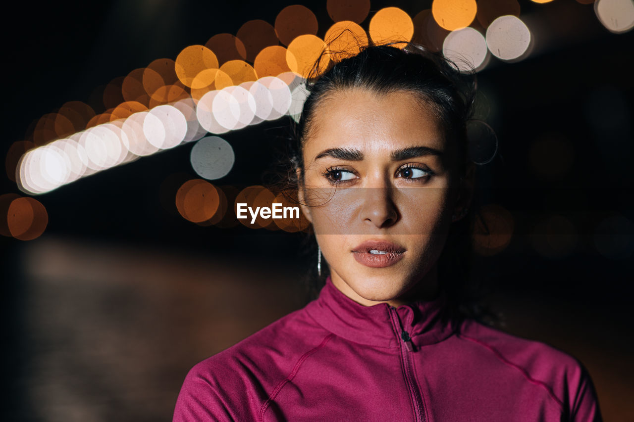 Portrait of young woman looking away at night