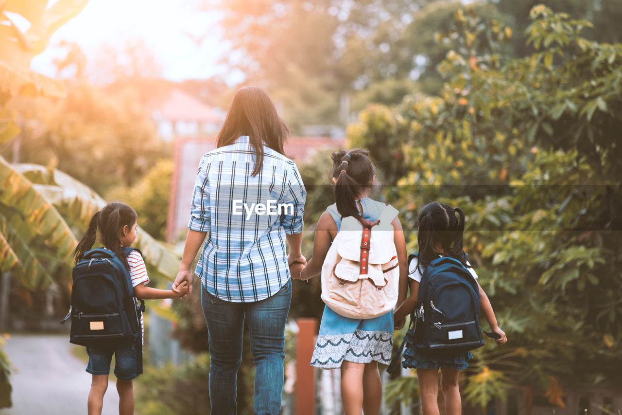 Rear view of girls with backpacks standing outdoors