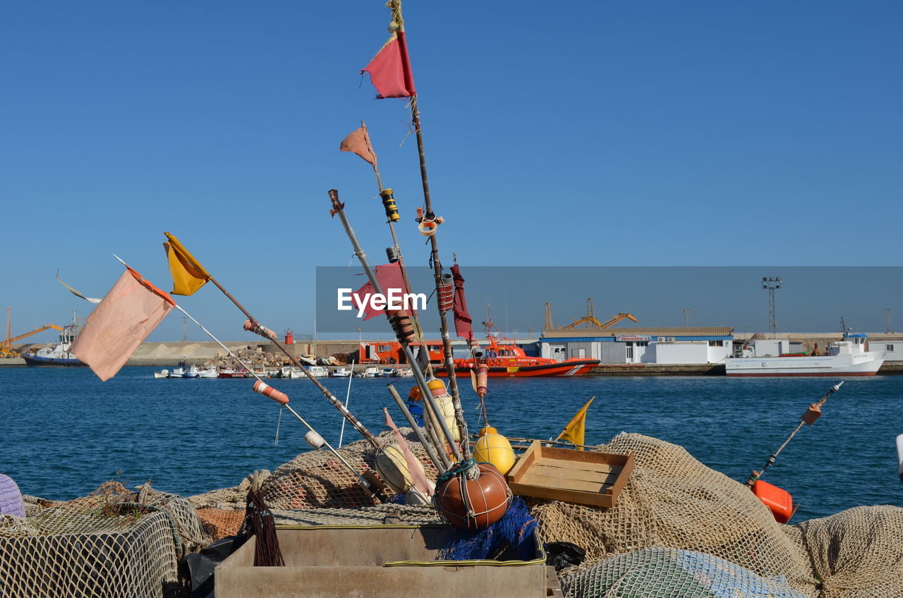Buoys and fishing nets at harbor against clear sky