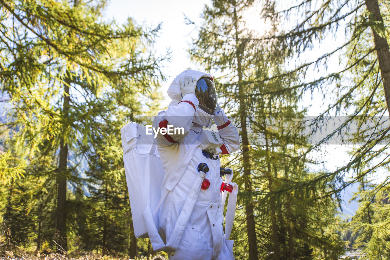 Astronaut looking away while standing in forest