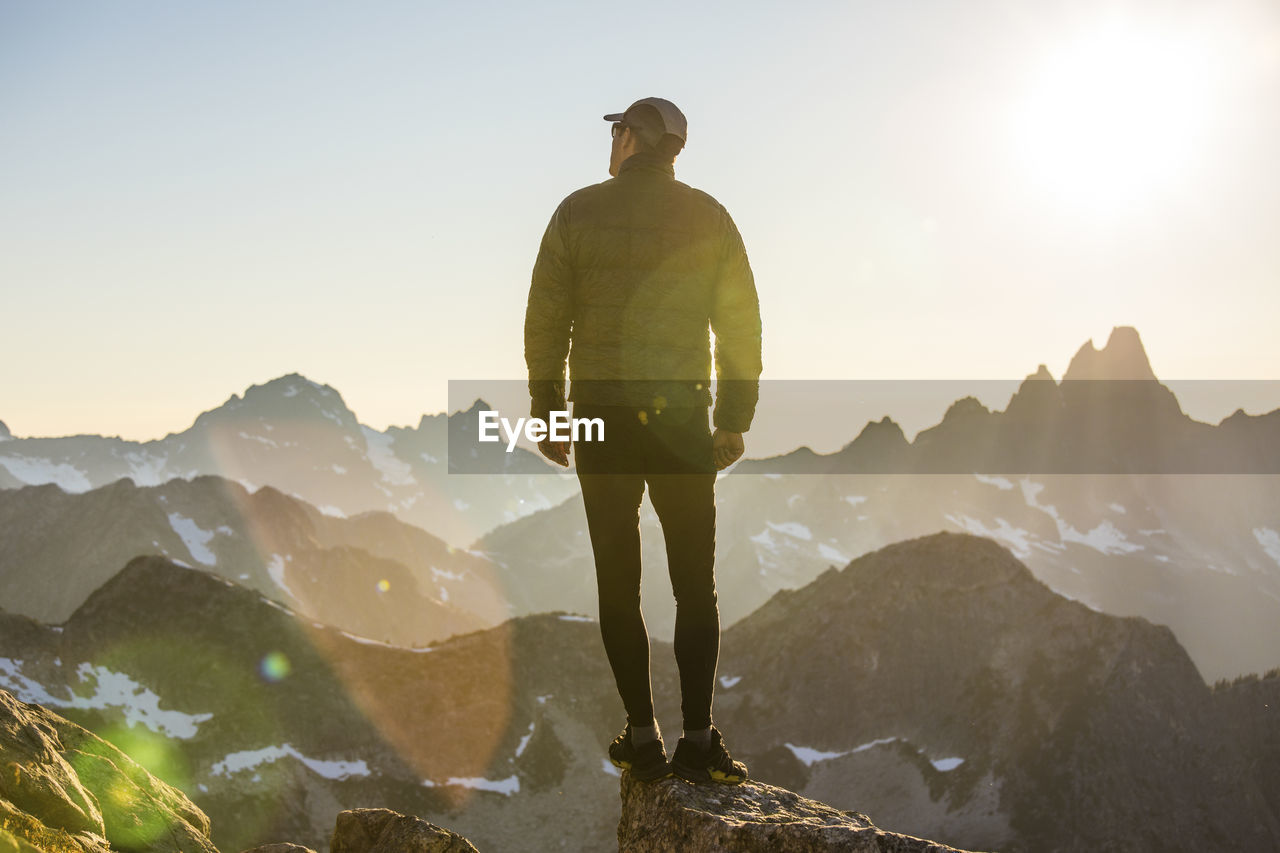 Lone hiker on mountain summit at sunset with view.