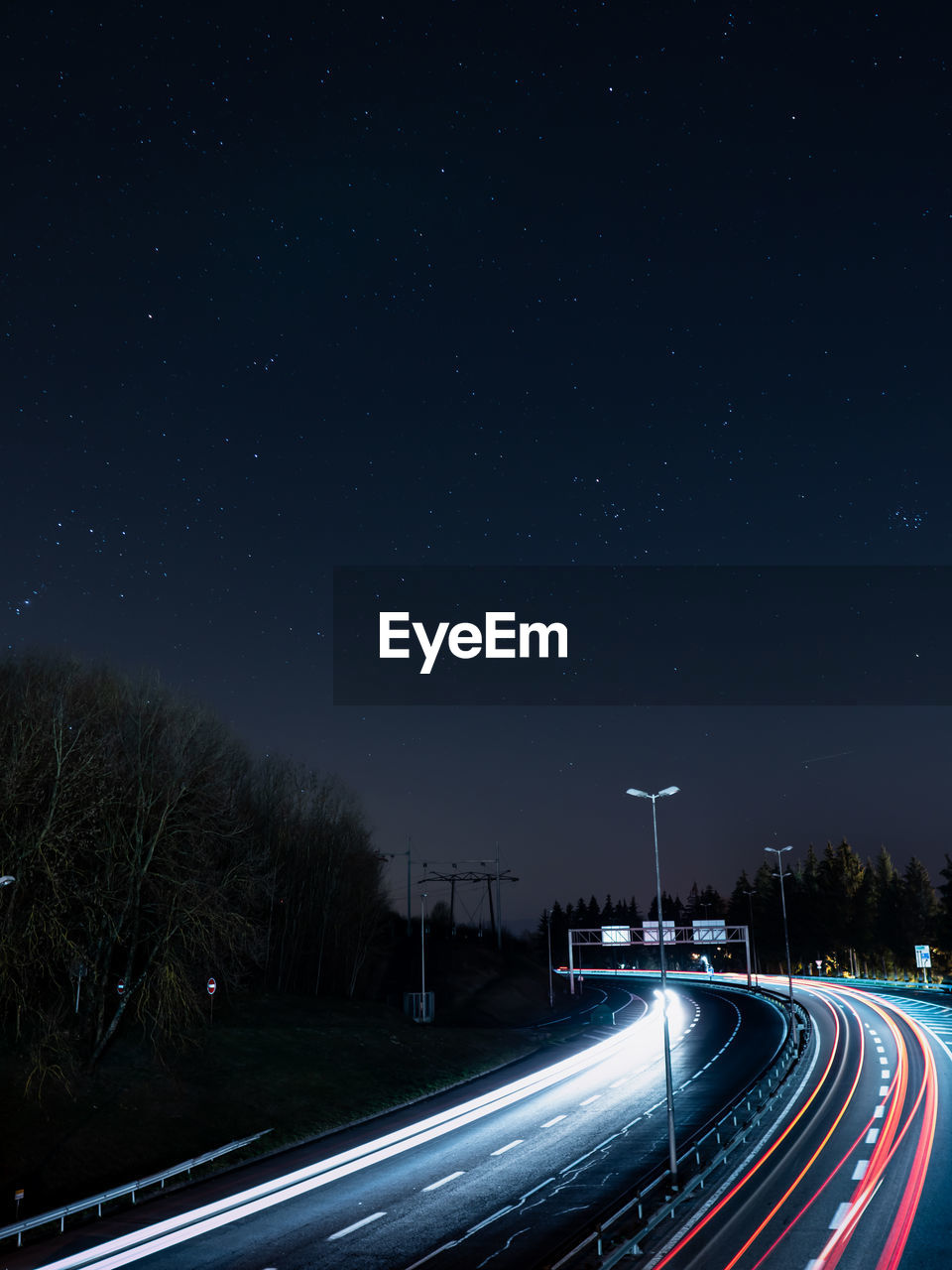 Light trails on road against sky at night