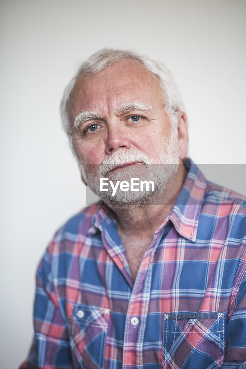 Portrait of senior therapist against white wall at home office