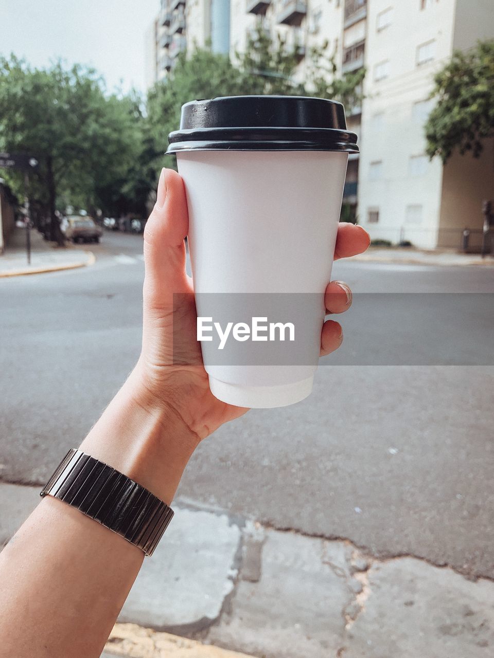 Cropped hand of person holding a coffee cup to go