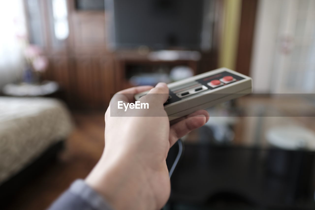 Cropped hand of person holding video game remote control