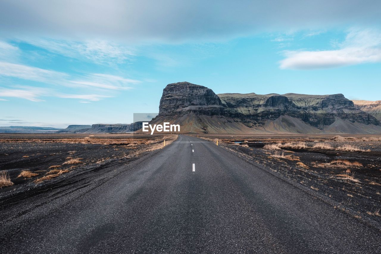 SCENIC VIEW OF ROAD BY MOUNTAIN AGAINST SKY