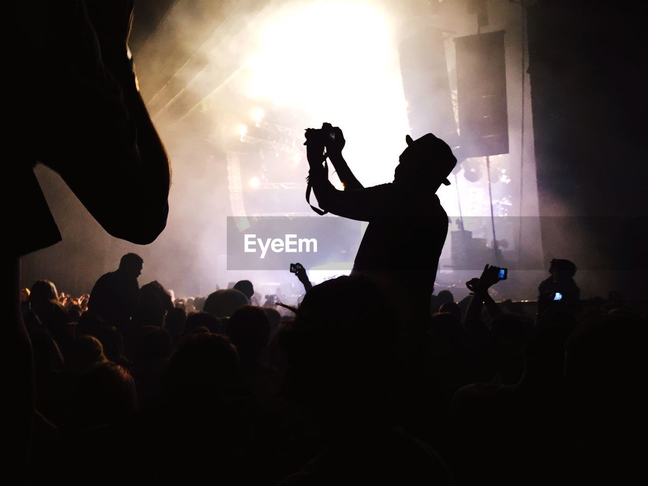Man photographing people enjoying music concert