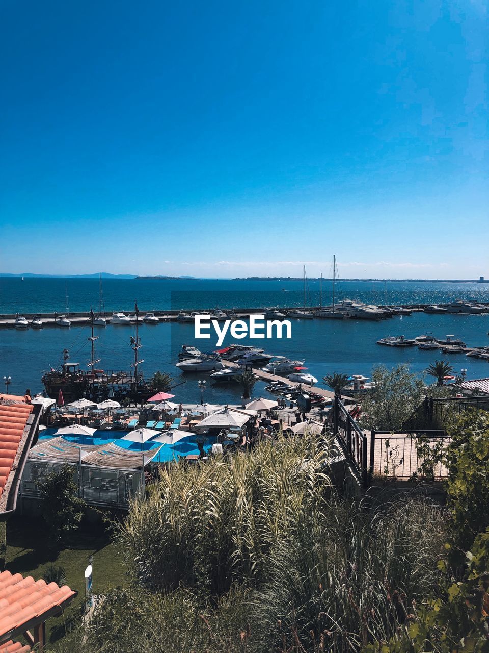 BOATS MOORED IN WATER AGAINST BLUE SKY