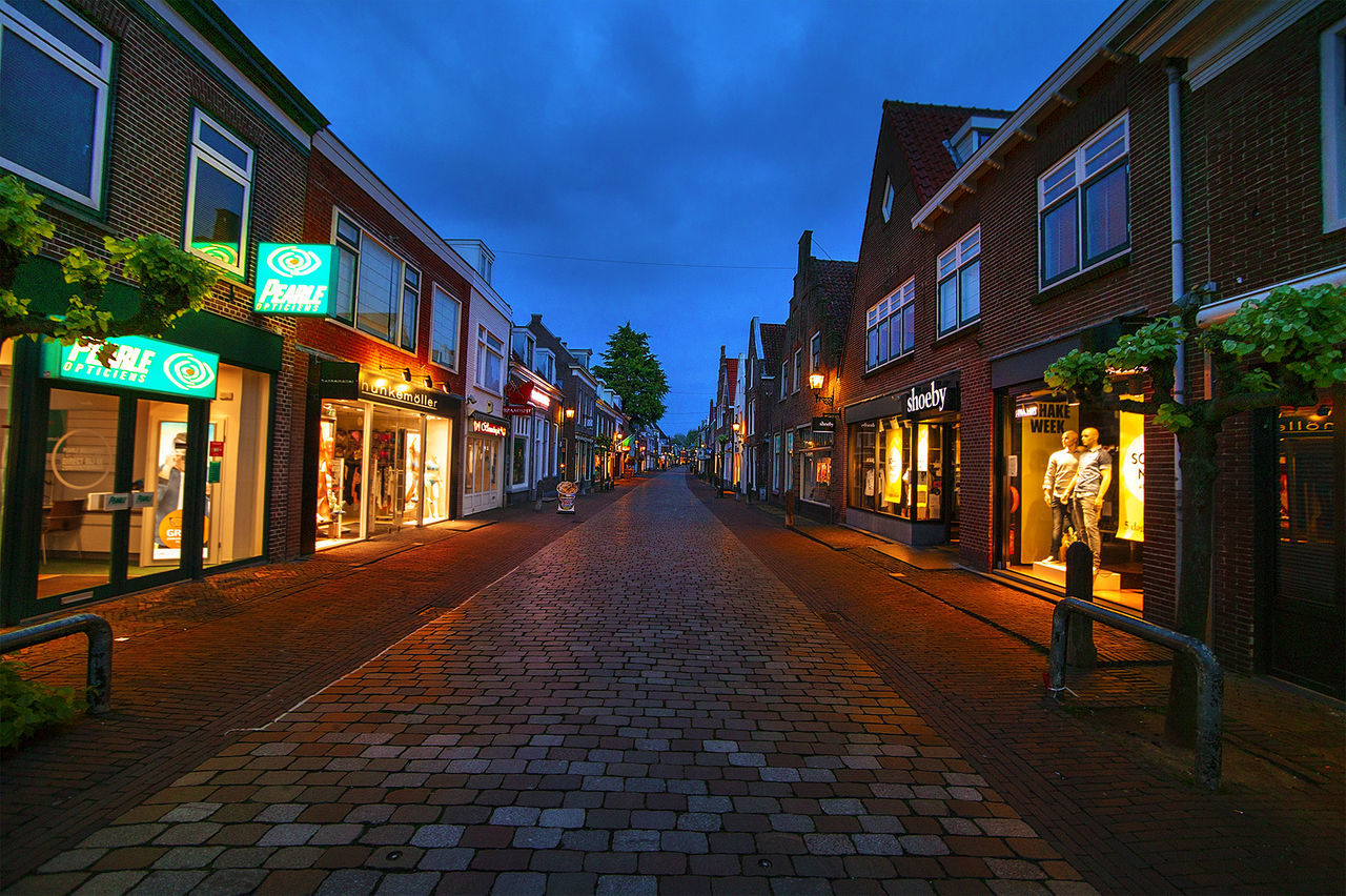 STREET AMIDST ILLUMINATED CITY AGAINST SKY