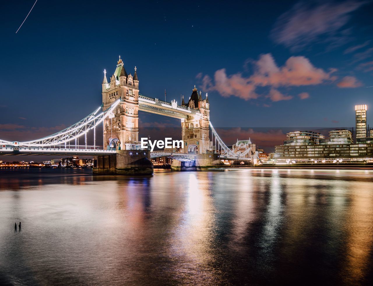 Illuminated tower bridge over thames river against sky at night