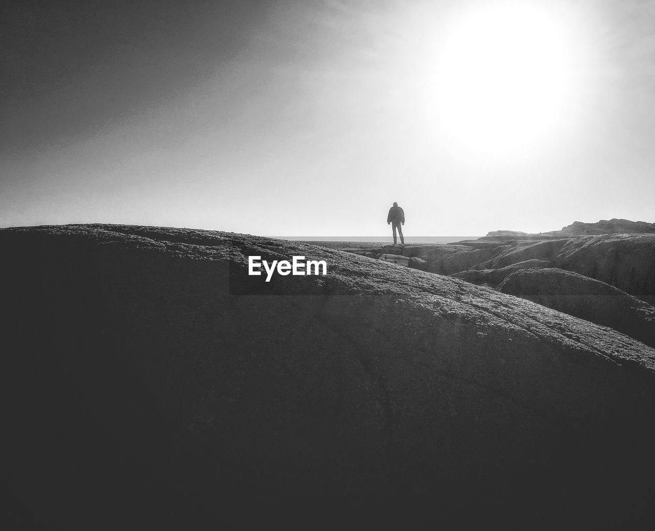 MAN STANDING IN DESERT AGAINST CLEAR SKY