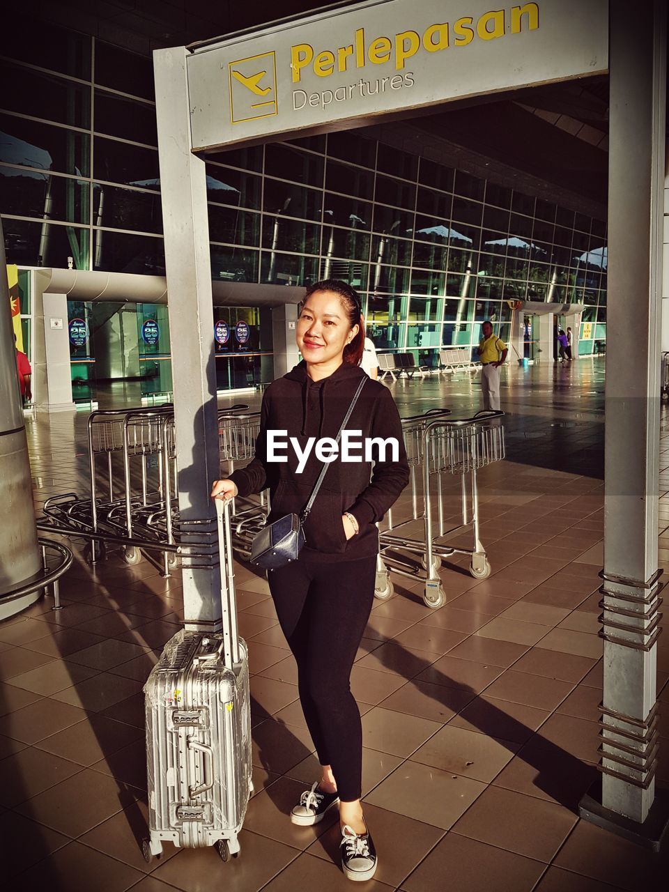 Portrait of smiling woman standing outside airport