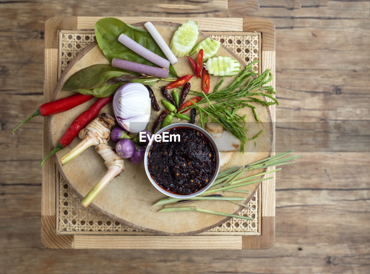 HIGH ANGLE VIEW OF VEGETABLES AND CUTTING BOARD ON WOOD