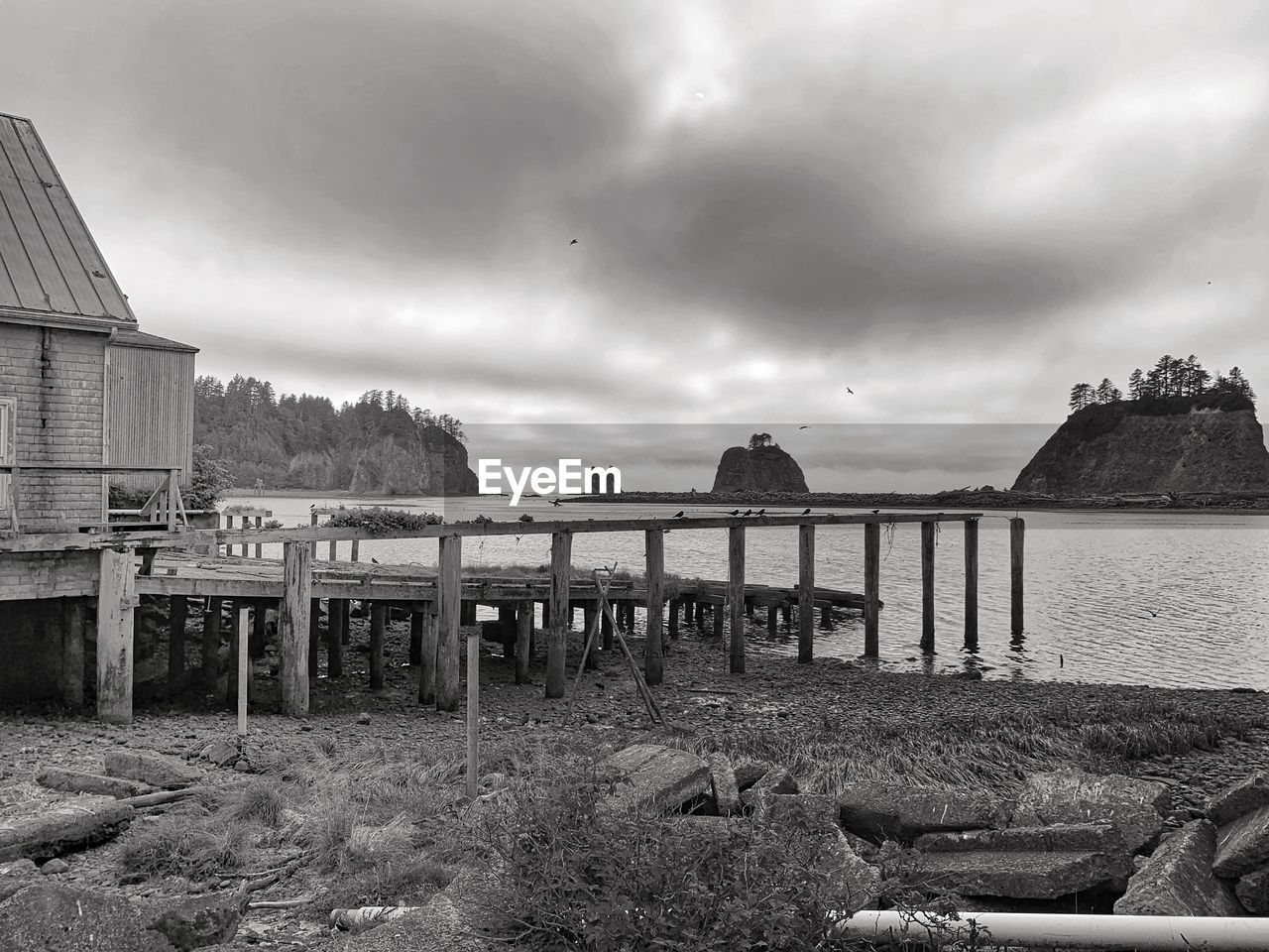 WOODEN POSTS AT BEACH AGAINST SKY