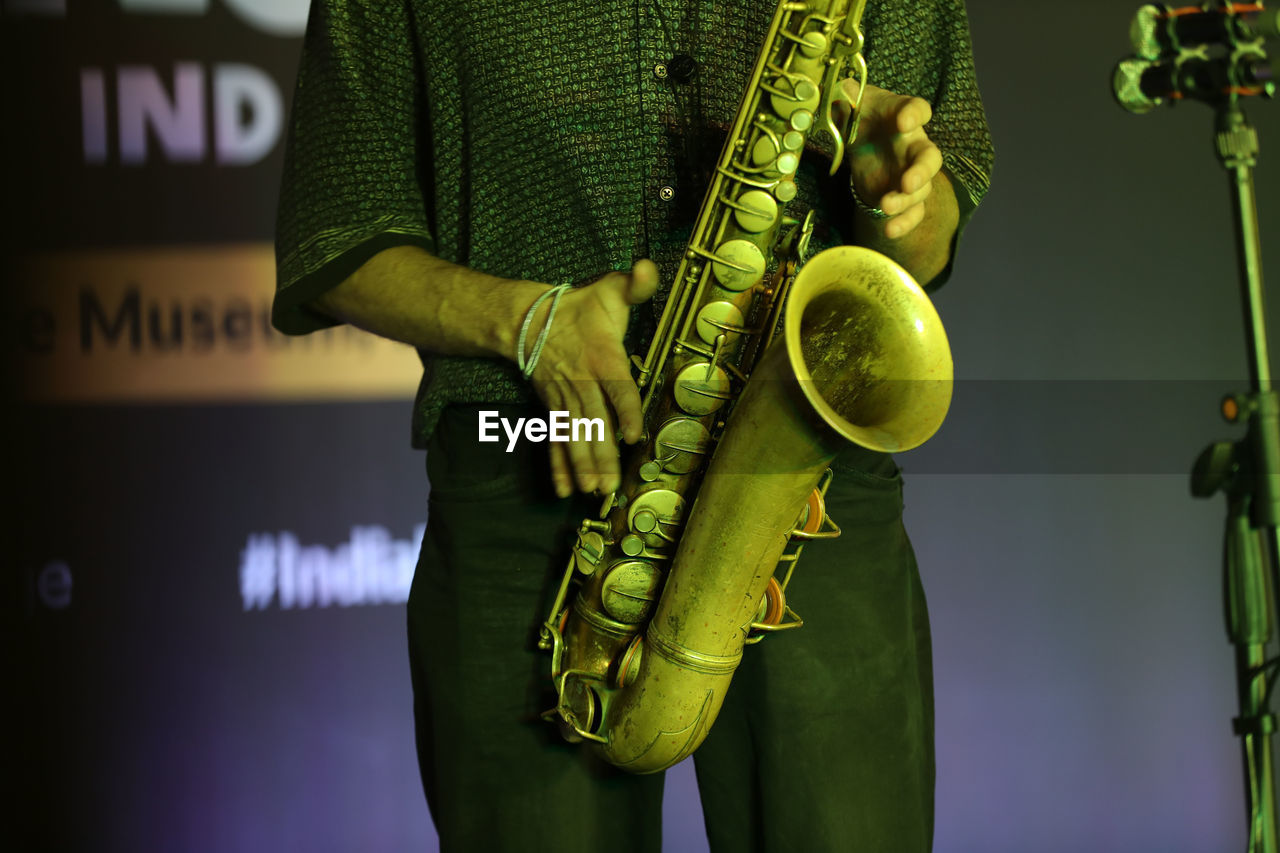 green, musical instrument, music, one person, musician, arts culture and entertainment, saxophone, yellow, adult, guitar, men, performance, musical equipment, electric guitar, holding, standing, concert, occupation, event