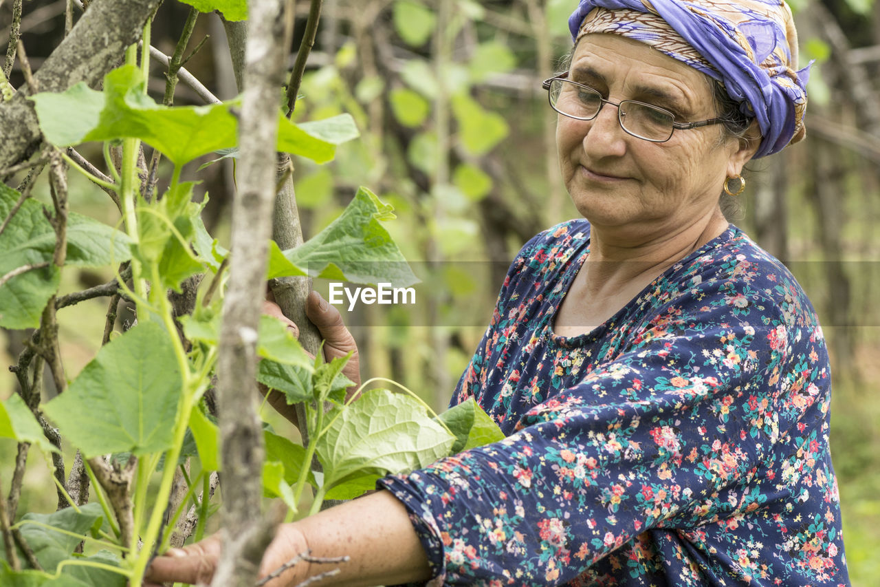 Smiling woman standing by plants on field