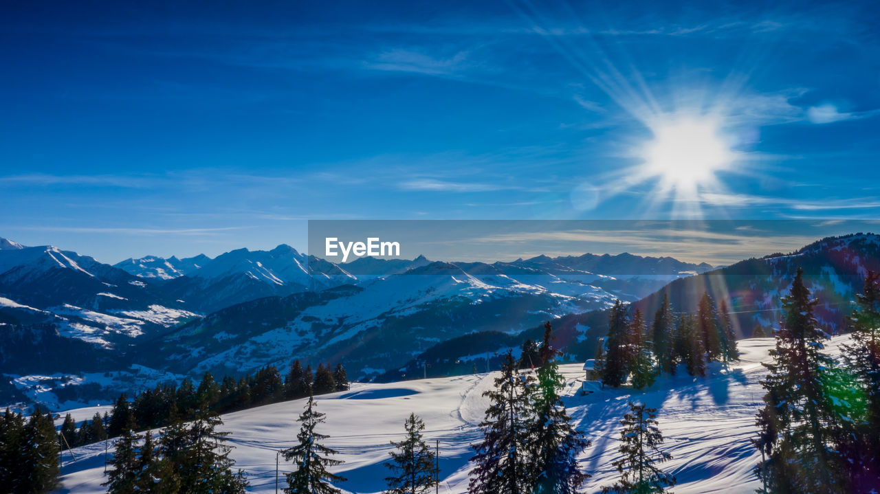 SCENIC VIEW OF SNOWCAPPED MOUNTAINS AGAINST BRIGHT SUN