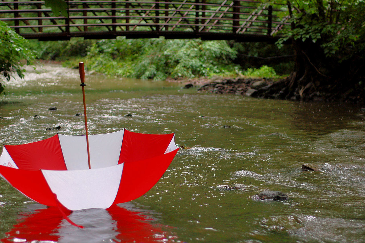 Upside down striped red and white umbrella on river