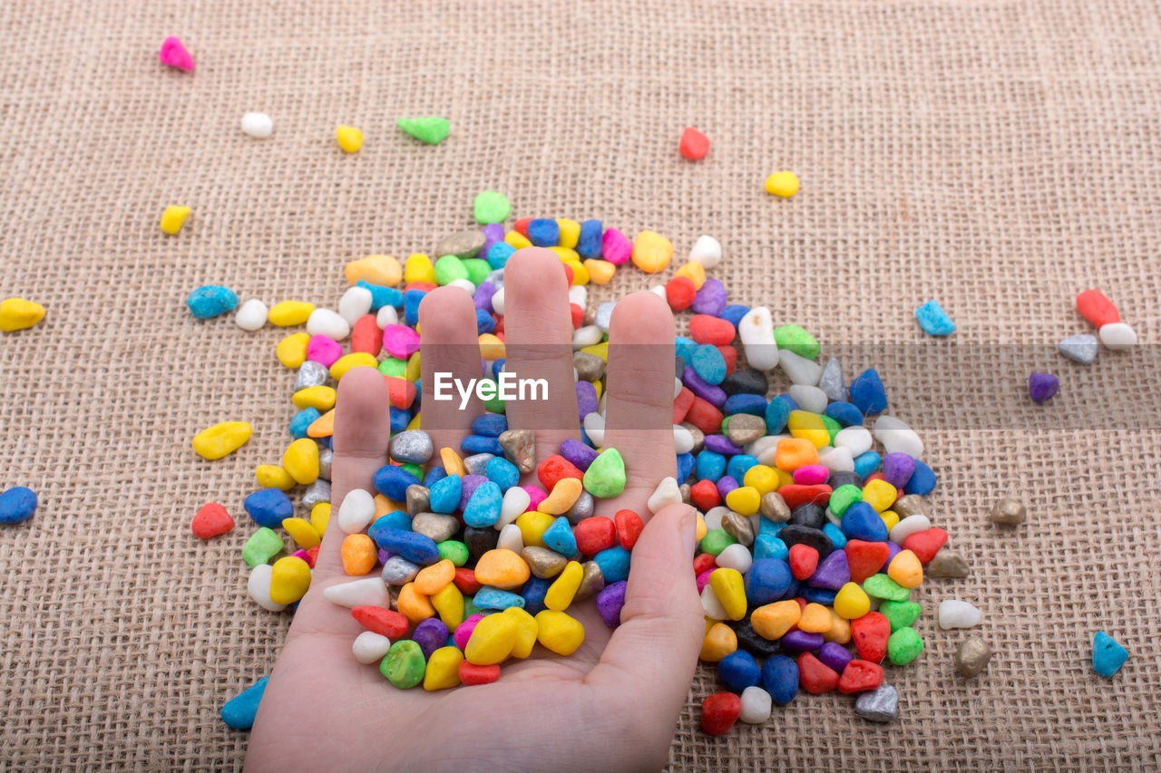 Close-up of hand holding colorful stones at table