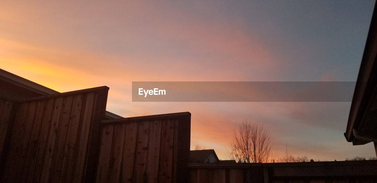 LOW ANGLE VIEW OF SILHOUETTE HOUSE AND BUILDING AGAINST SKY DURING SUNSET